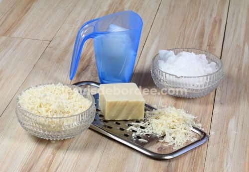 Ingrédients pour une recette de lessive maison : savon de Marseille râpé, cristaux de soude et doseur