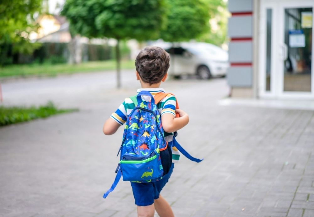 Enfant avec un cartable se dirigeant vers l'école pour la rentrée scolaire