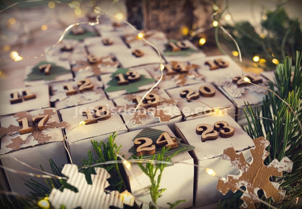 Calendrier de l'avent à remplir : petites boîtes blanches numérotées en bois, guirlande lumineuse et branches de sapin