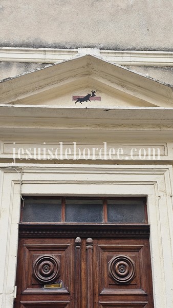 Façade typique de Vauvert avec une porte en bois et un taureau noir dessiné sur le fronton